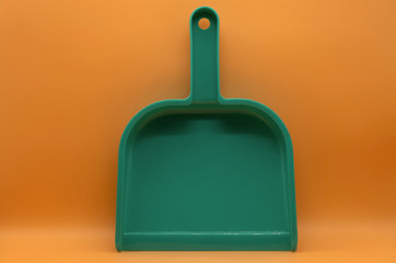 Green small dustpan To clean in the house With an orange backdrop