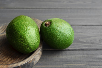 Two organic fresh avocado in wooden plate over dark wooden background