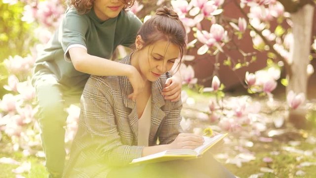 Mom and son have fun in the spring meadow. Blooming magnolia, happy family, mother's day