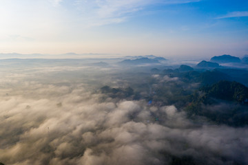 Fototapeta premium Aerial view of mountains with cloud cover mountain at sunrise and blue sky in Surat Thani Province, Thailand.