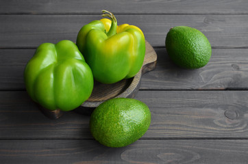 Fresh avocados and green peppers vegetables on wooden rustic background. Source of vegetable protein, healthy food.