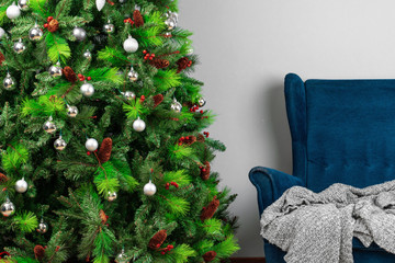 Holiday interior. Beautiful decorated christmas tree with blue armchair