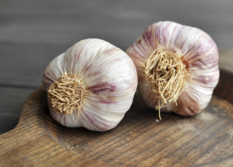 Two dry garlic bulbs in wooden plate on old dark wooden background