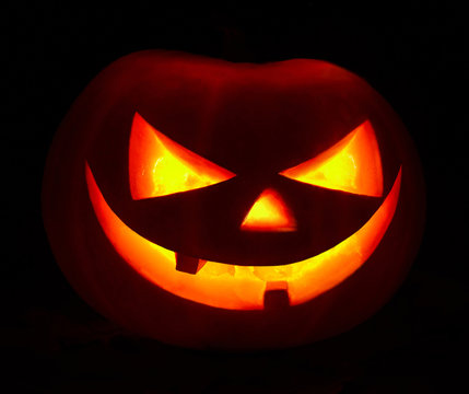 Jack O'Lantern face glowing in the dark. Haloween pumpkin on black background.