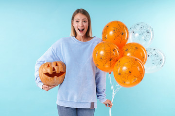 Image of caucasian woman holding halloween carved pumpkin and air balloons
