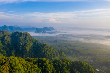 Naklejka premium Aerial view of mountains with cloud cover mountain at sunrise and blue sky in Surat Thani Province, Thailand.