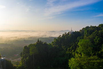 Aerial view of mountains with cloud cover mountain at sunrise, blue sky, pagoda on the mountain in Surat Thani Province, Thailand.