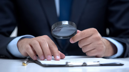 Attorney reading document with magnifier, studying case in detail, investigation - 297794817