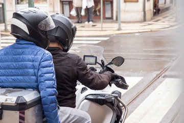 A woman and a man traveling by motorcycle finding the location on the navigator device, sitting on their motorcycle