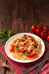 Pasta carbonara with tomato sauce and minced meat, grated parmesan cheese and fresh parsley - homemade healthy italian pasta on rustic wooden background. 