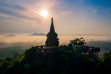 Aerial scenery of pagoda on the mountain with cloud at sunrise in the morning in Surat Thani province, Thailand