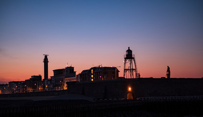 Fototapeta na wymiar skyline of vlissingen with lighthouse and the statue of willem de ruyter in the evening colors