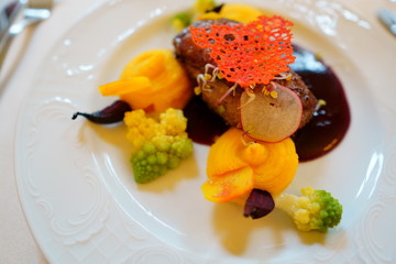 main course in the restaurant. The food is nicely laid on a white plate with a delicate pattern. mouth-watering dish and beautiful play of colors