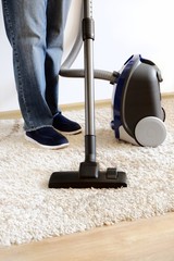 Carpet cleaning with a vacuum cleaner in the house. Cleaner legs close up. Homework concept. Copy space for text.