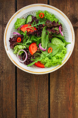 Healthy salad, leaves mix salad (mix micro greens, cucumber, tomato, onion, other ingredients) menu concept. food background. copy space. Top view