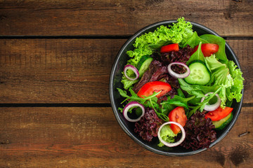 Healthy salad, leaves mix salad (mix micro greens, cucumber, tomato, onion, other ingredients) menu concept. food background. copy space. Top view
