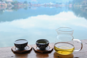 Hot Tea put on wood floor look at reservoir in the morning time ,Beautiful land Location's Rakthai village at the sunrise time , Mae Hong Son province in Thailand
