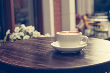 View of a summer terrace cafe with cup of cappuccino on the table.