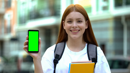 Happy female student showing green screen phone, online university schedule, app