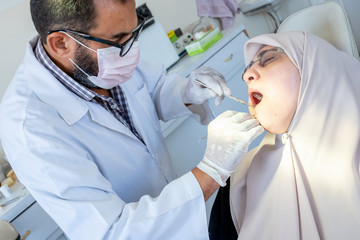 Dentist treating his patient teeth from ache