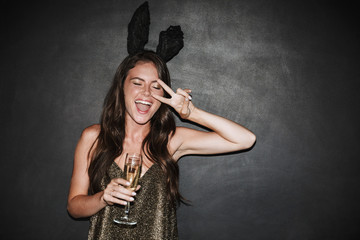 Image of woman holding glass of champagne while gesturing peace sign