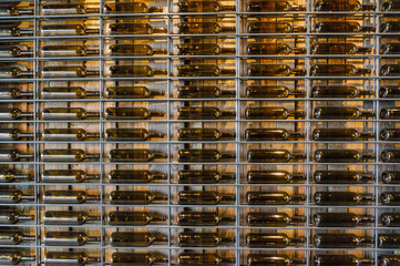 Many glass wine bottles on wine shelves with lighting. Interior in the restaurant. Color