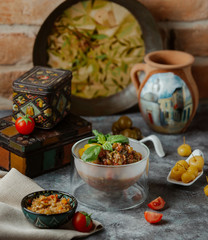 aubergine salad in creative glass bowl next to pickles