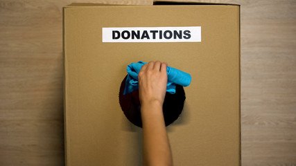 Woman putting used clothing in cardboard box for donations, charity organization