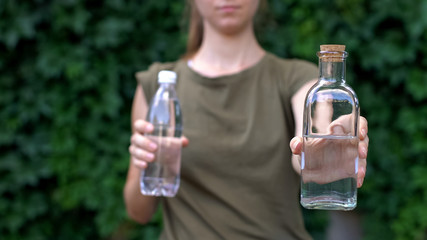 Responsible lady choosing reusable glass bottle instead of plastic, save planet