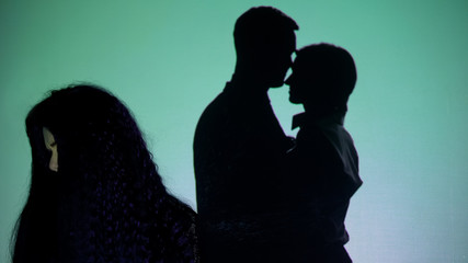 Crying girl turning head from silhouette couple kissing on background, betrayal