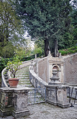 Fototapeta na wymiar Beautiful scene with curved ancient stone stair going upwards in an old Italian park