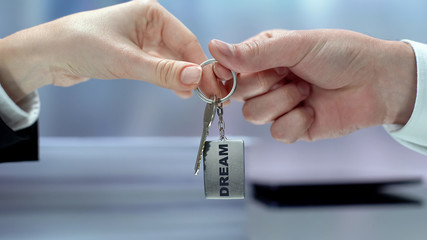 Hand giving keychain, female accepting challenge, inspiration and dream goal