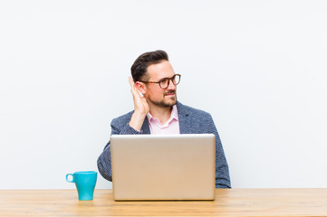 young handsome businessman looking serious and curious, listening, trying to hear a secret...