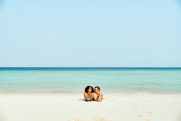 Fototapeta na wymiar Two woman in bikinis lying on a sandy tropical beach