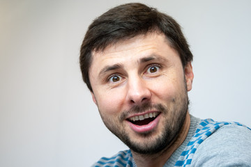 Obraz premium Overjoyed smiling handsome bearded man looks surprised in camera