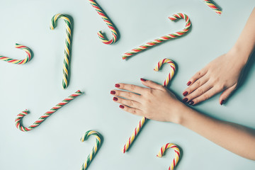 Beauty and food pattern with female hands and multi-colored candy canes. Christmas layout.