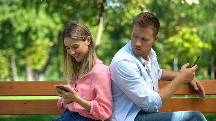 Fototapeta na wymiar Jealous man checking girlfriend phone reading messages, couple distrust conflict