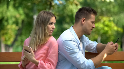 Obraz premium Girlfriend feeling jealous of boyfriend reading phone correspondence, betrayal