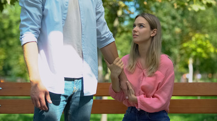Obraz premium Man leaving upset girlfriend alone on bench in park walking away, break-up