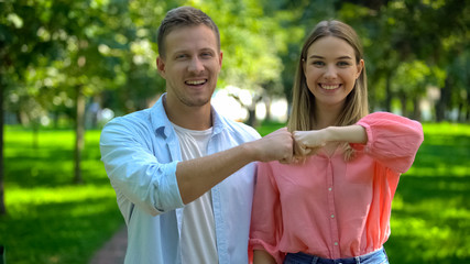 Smiling man and woman bumping fists at park, good old friendship, togetherness