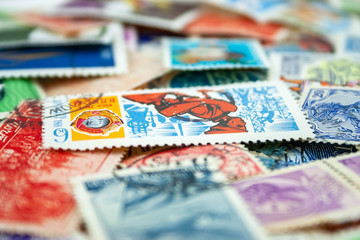 Closeup view on a variety of multi-colored postage stamps from different countries and years. Selective focus