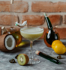 kiwi cocktail in crystal glass with long stem garnished with coconut piece