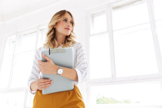 Image of successful elegant secretary woman holding clipboard in office