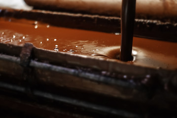 molten chocolate poured into a tray in a confectionery factory, close-up
