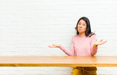 young  pretty latin woman feeling puzzled and confused, unsure about the correct answer or...