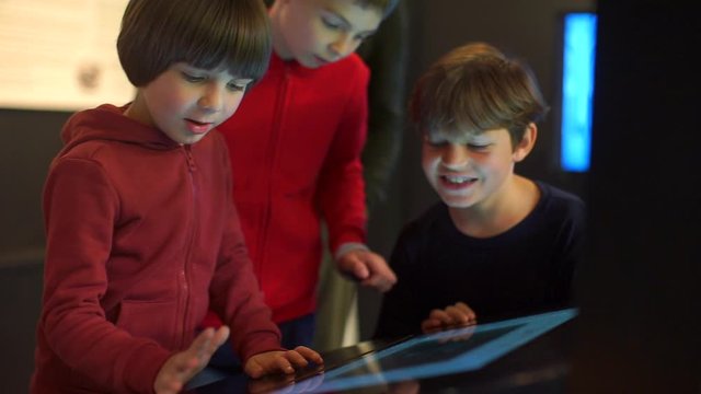 Three brothers stand near the touch keyboard, monitor