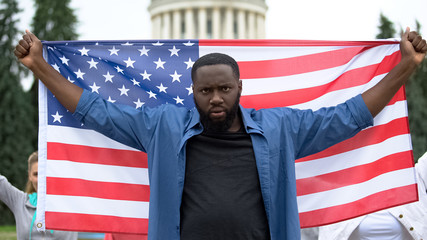 Angry afro-american man holding US flag, national strike against war, for peace