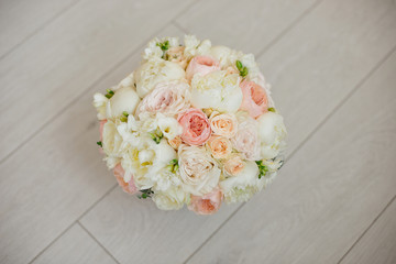 Wedding bouquet lying on grey carpet during preparation before celebration. Side view of decorative rose,peonies flowers and leaves bouquet.