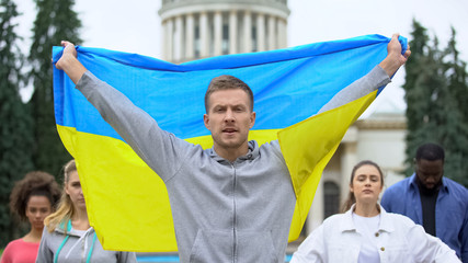 Activists raising Ukrainian flag chanting slogan, independence rally, patriotism