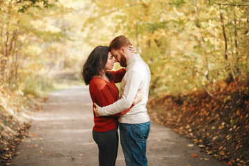 Portrait of beautiful couple man woman in love. Boyfriend and girlfriend hugging outdoor in park road path on autumn fall day. Togetherness and happiness. Authentic real people feelings.